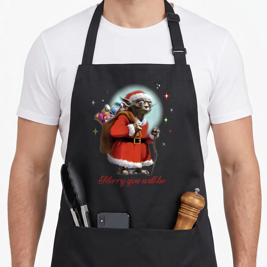 Yoda santa apron - Realistic Yoda in red Santa suit holding cane and gift sack with Merry you will be text — shown on a black cotton canvas apron against a white background