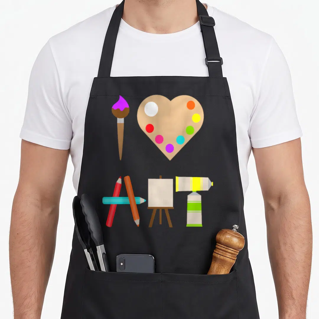 Colorful craft apron - Cartoon art supplies including heart palette, easel, pencils, and paint tubes — shown on a black cotton canvas apron against a white background