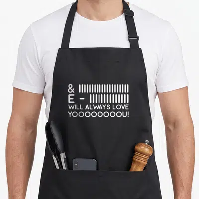 Movie lyricist apron - White barcode style lines above WILL ALWAYS LOVE YOOOOOOOOOU! text — shown on a black cotton canvas apron against a white background
