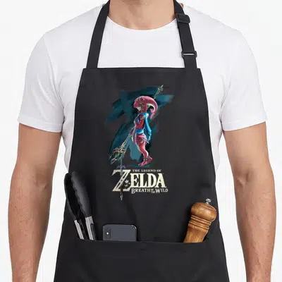 Breath paint apron - Mipha character holding spear in red blue with Legend of Zelda text below — shown on a black cotton canvas apron against a white background