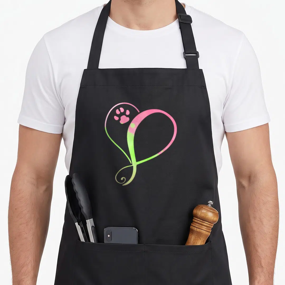 Cat dog cooking apron - Pink and lime green heart outline with a paw print inside the upper left curve — shown on a black cotton canvas apron against a white background