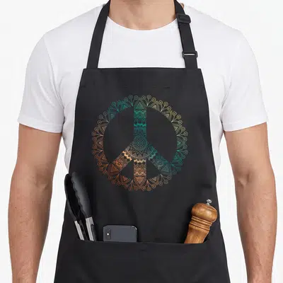 Neutral boho apron - Mandala line-art peace symbol in teal, orange, and yellow gradients — shown on a black cotton canvas apron against a white background