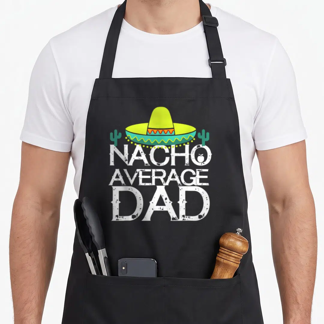 Nacho cinco apron - Lime green sombrero over white Nacho Average Dad text flanked by two cacti — shown on a black cotton canvas apron against a white background