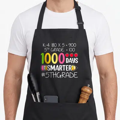 Smarter fifth teacher apron - Colorful 1000 days math equation with three red apples and pencil graphic on black fabric — shown on a black cotton canvas apron against a white background