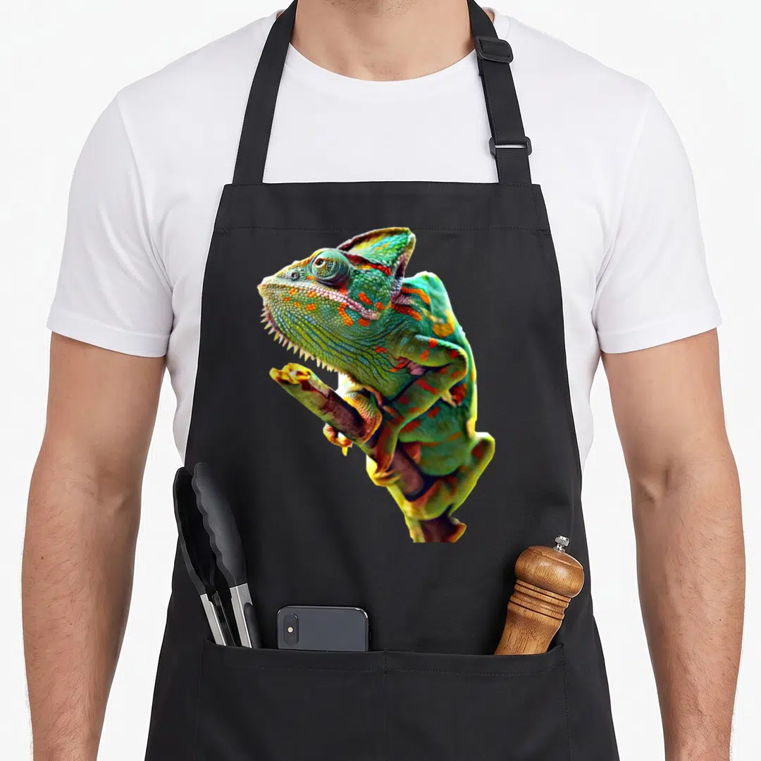 Scary chameleon apron - Realistic photo of a green veiled chameleon with orange and blue markings perched on a branch — shown on a black cotton canvas apron against a white background