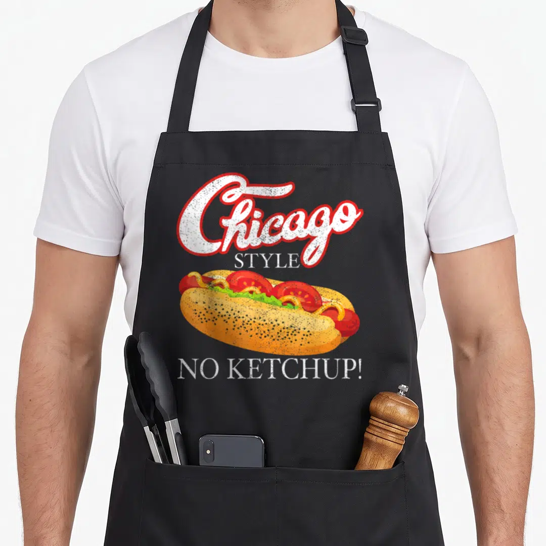 Chicago 4th of july apron - Cartoon hot dog with mustard relish and text Chicago Style No Ketchup — shown on a black cotton canvas apron against a white background
