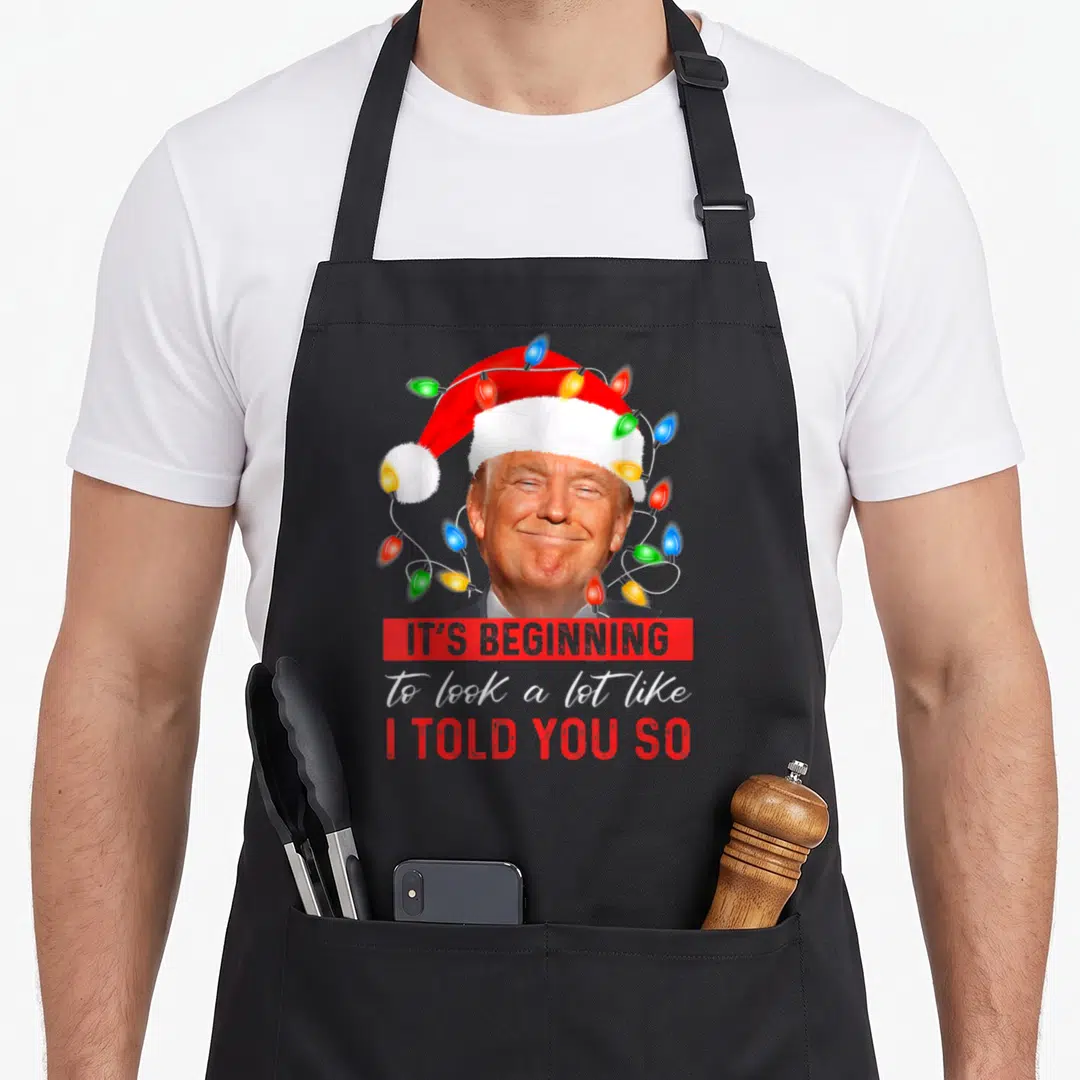 Beginning xmas apron - Donald Trump Santa hat lights IT'S BEGINNING I TOLD YOU SO text — shown on a black cotton canvas apron against a white background