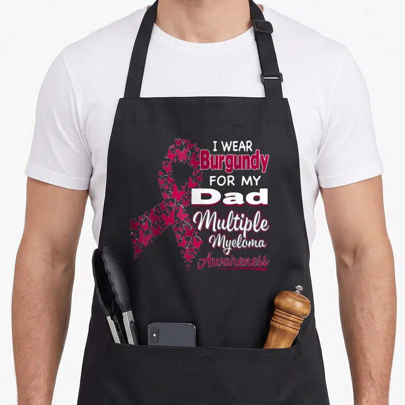 Funny multiple myeloma awareness apron - Burgundy butterfly awareness ribbon with I Wear Burgundy For My Dad text — shown on a black cotton canvas apron against a white background