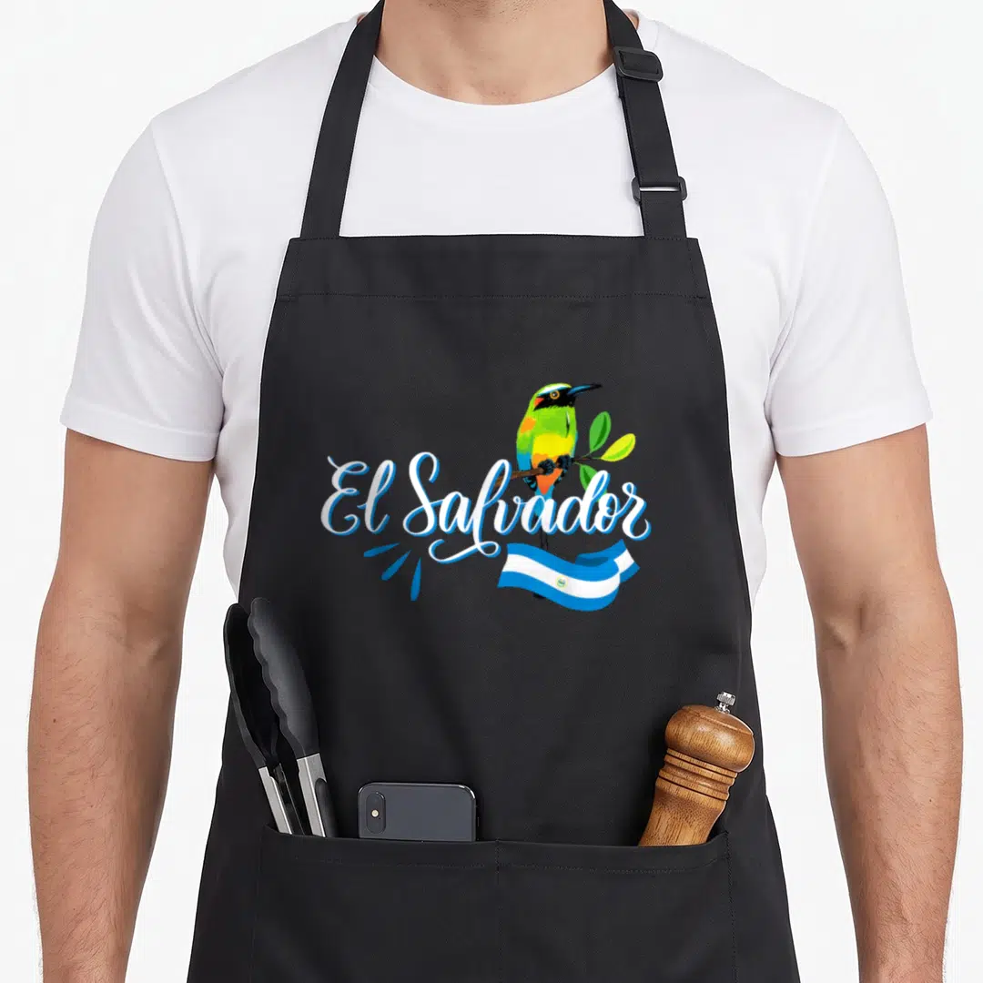 Solo salvadoran apron - Cartoon bird perched on branch with El Salvador script and waving flag in white blue green — shown on a black cotton canvas apron against a white background