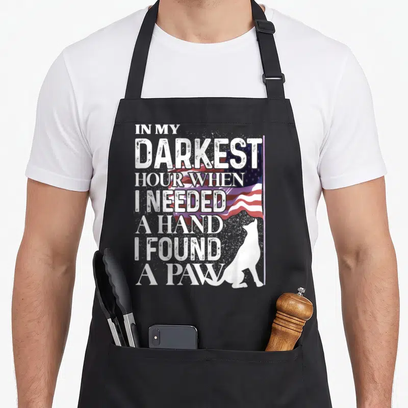 Darkest hand apron - Distressed text over waving US flag with white sitting dog silhouette — shown on a black cotton canvas apron against a white background