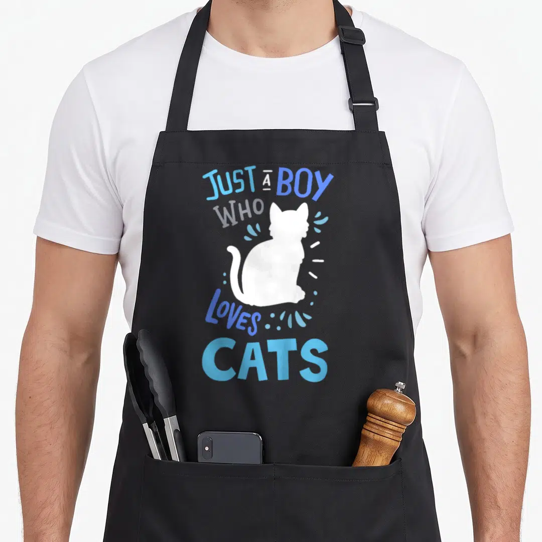 Cool general cat apron - White cat silhouette with blue text Just A Boy Who Loves Cats and scattered droplets — shown on a black cotton canvas apron against a white background