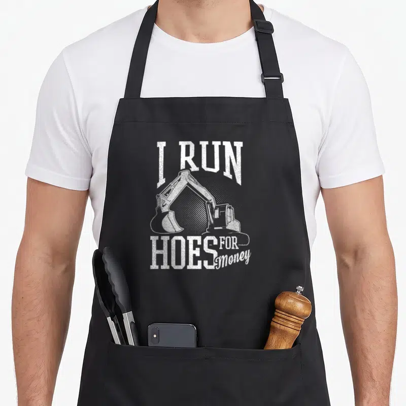 Run heavy canvas aprons - White distressed I RUN HOES FOR Money text framing an excavator silhouette — shown on a black cotton canvas apron against a white background