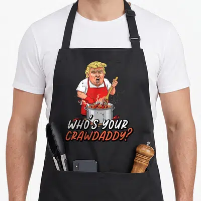 Crawdaddy crawfish apron - Cartoon man in red apron stirring crawfish pot with text WHO'S YOUR CRAWDADDY — shown on a black cotton canvas apron against a white background