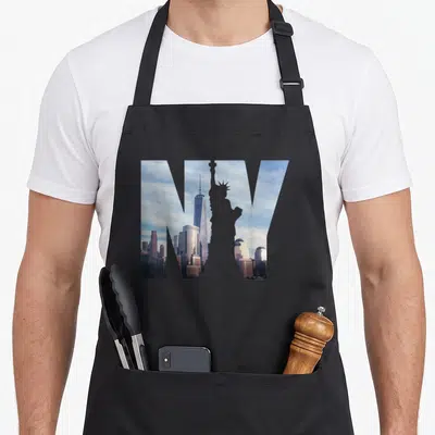 Vintage skyline new york apron - Large NY letters filled with photo of Statue of Liberty and One WTC skyline — shown on a black cotton canvas apron against a white background