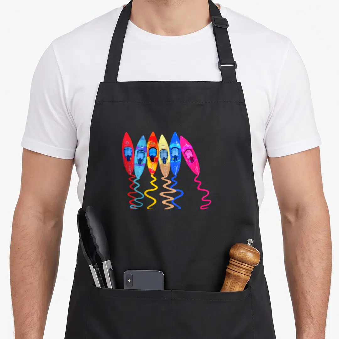 Outdoor colorful aprons - Six cartoon kayaks in red blue orange yellow pink with wavy lines below — shown on a black cotton canvas apron against a white background