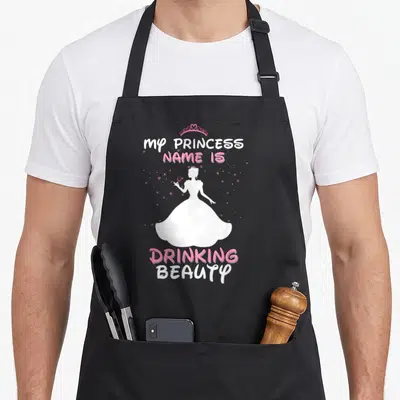Princess wine apron - White princess silhouette holding wine glass with pink stars and text My Princess Name is — shown on a black cotton canvas apron against a white background