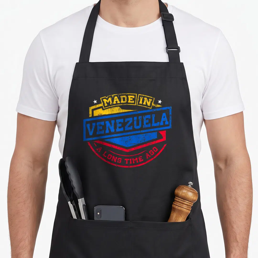 Venezuela aboriginal apron - Yellow blue and red stamp reading Made In Venezuela A Long Time Ago with two white stars — shown on a black cotton canvas apron against a white background