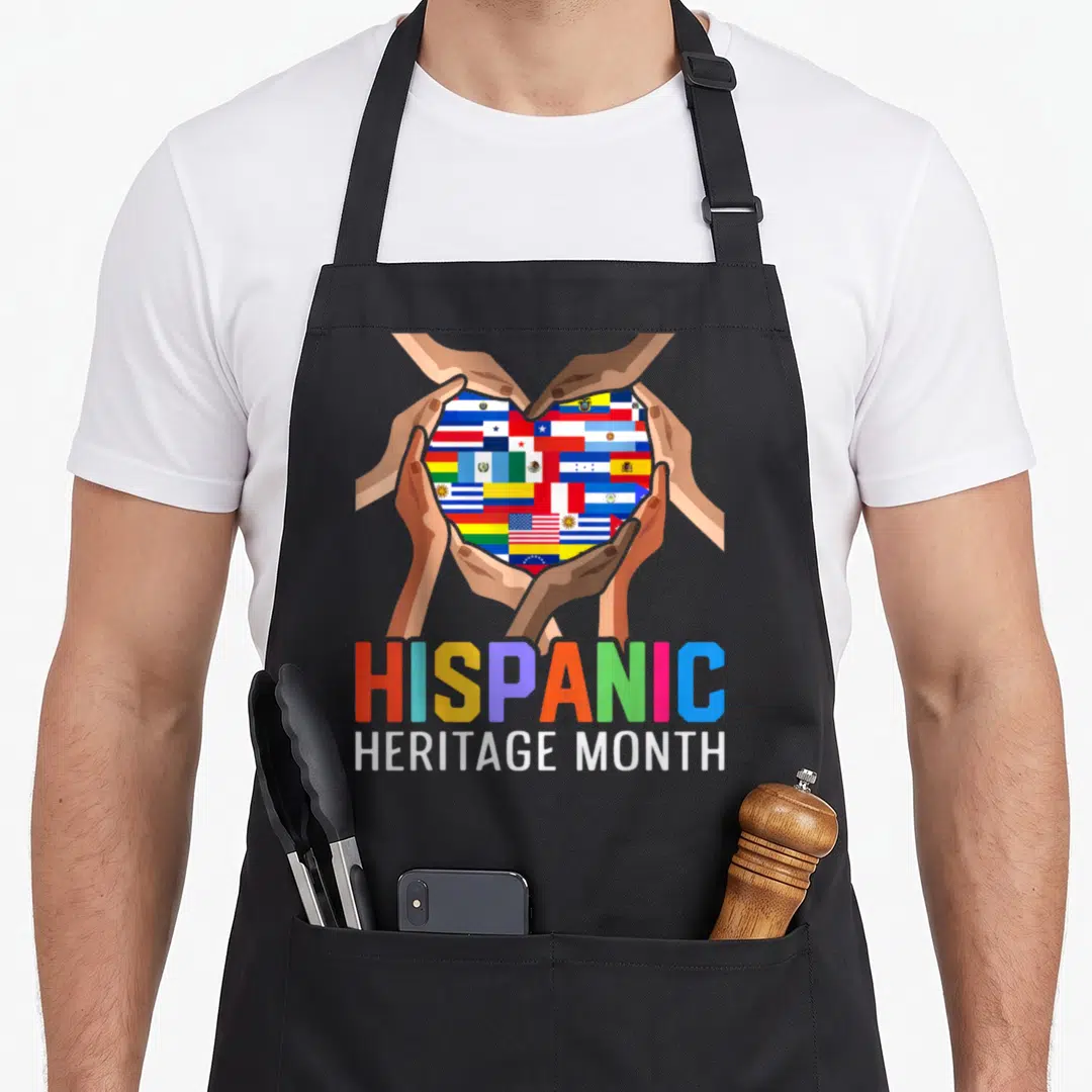 Latin country apron - Four hands holding heart of flags with Hispanic Heritage Month text — shown on a black cotton canvas apron against a white background