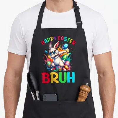 Bruh egg apron - Dabbing rabbit wearing sunglasses and sneakers surrounded by colorful easter eggs and paint splashes — shown on a black cotton canvas apron against a white background