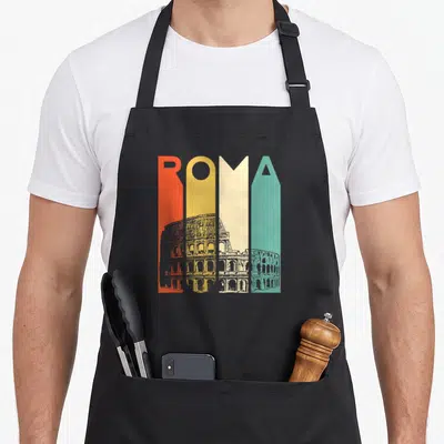 Roma italian apron - Colorful ROMA text with grey Colosseum sketch overlay across bottom half of letters — shown on a black cotton canvas apron against a white background