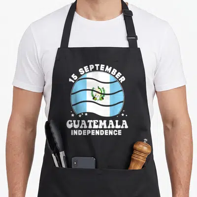 Independence guatemalan aprons - Circular Guatemala flag with arched 15 September text and stacked independence words — shown on a black cotton canvas apron against a white background