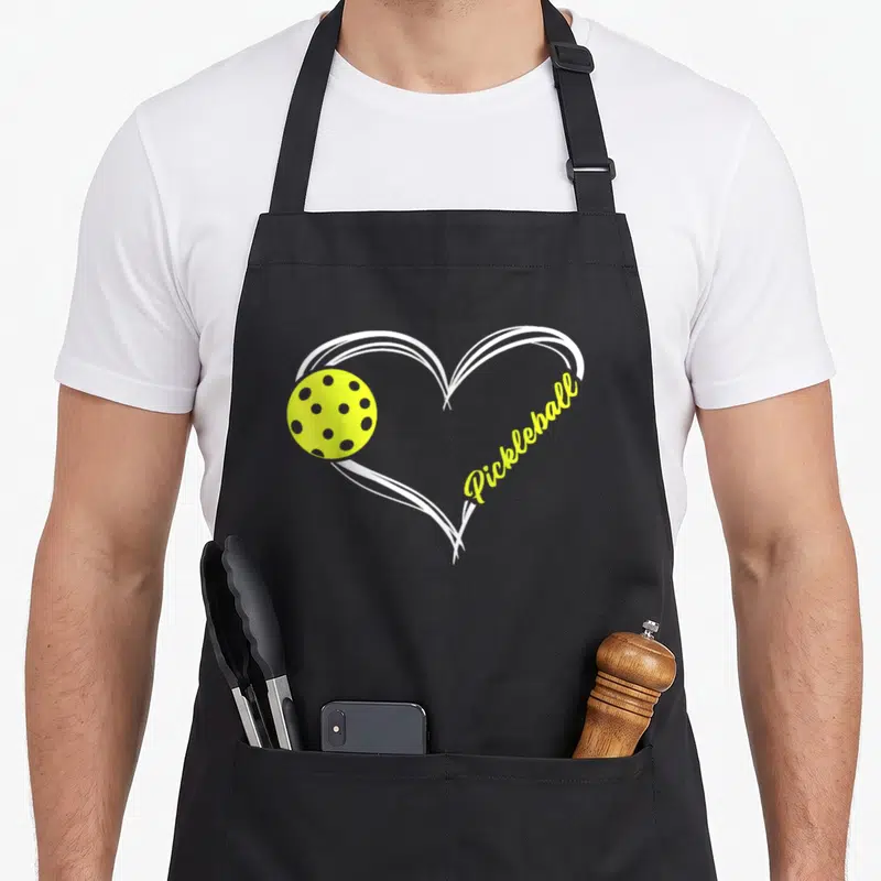 Match pickleball apron - Yellow pickleball inside white heart outline with Pickleball text — shown on a black cotton canvas apron against a white background