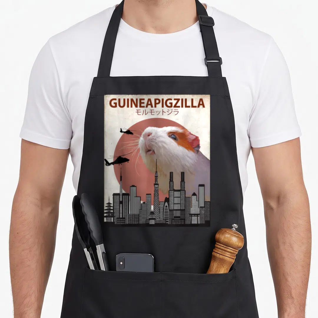 Guineapigzilla guinea dad apron - Giant guinea pig head over city skyline with helicopters and red sun — shown on a black cotton canvas apron against a white background