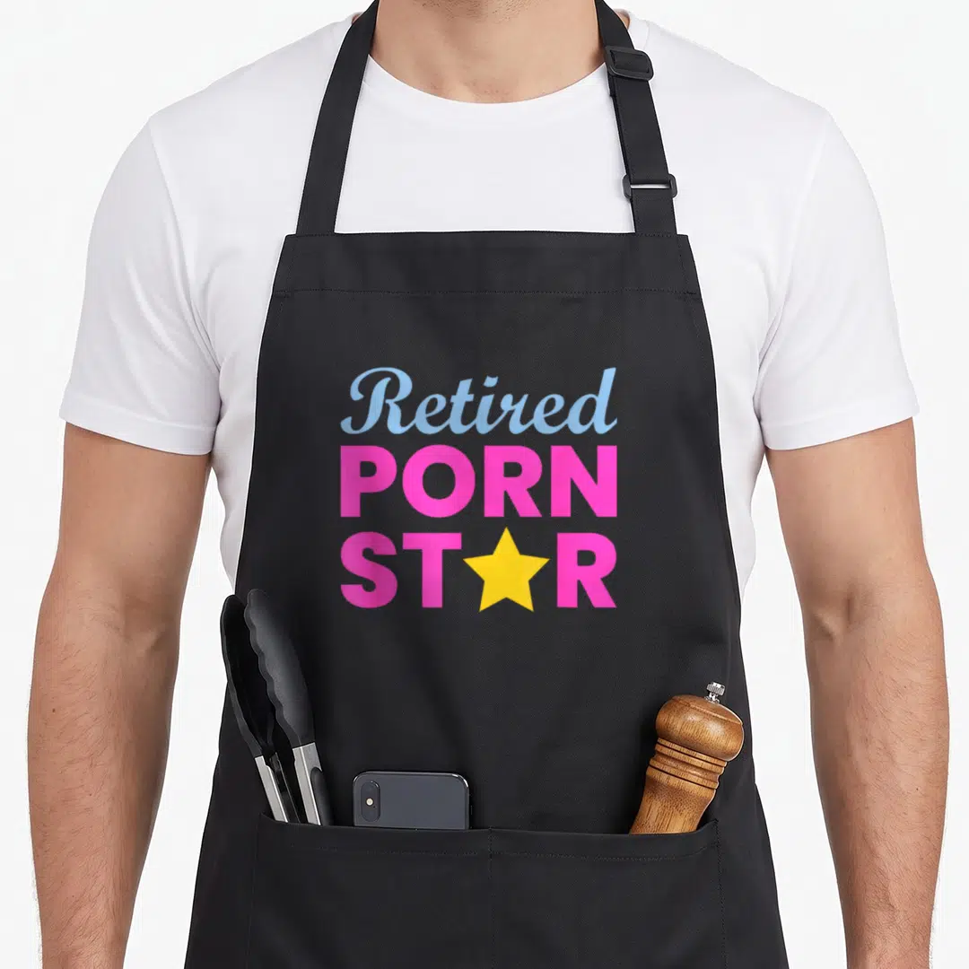 Star retirement apron - Stacked text reading Retired Porn Star with yellow star replacing letter — shown on a black cotton canvas apron against a white background