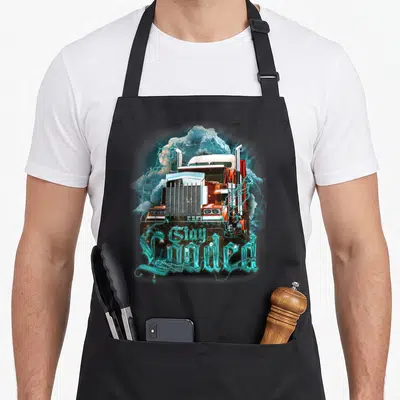 Truckin semi truck apron - Orange semi-truck with cyan lightning and clouds, text reads Gay Loaded in gothic font — shown on a black cotton canvas apron against a white background