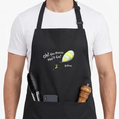 Youll novelty apron - Arched text Oh the Places You'll Go above yellow white striped balloon held by small figure — shown on a black cotton canvas apron against a white background
