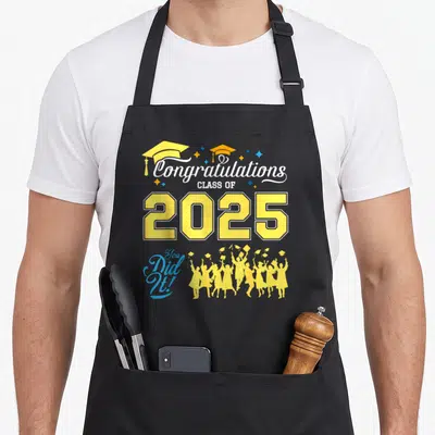 Class senior congrats apron - Vertical Class of 2025 text with yellow caps, blue stars, and celebrating student — shown on a black cotton canvas apron against a white background