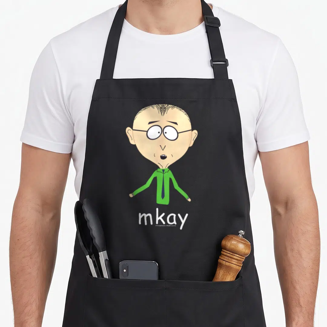 Mackey mr apron - Cartoon man in green shirt above white mkay text — shown on a black cotton canvas apron against a white background