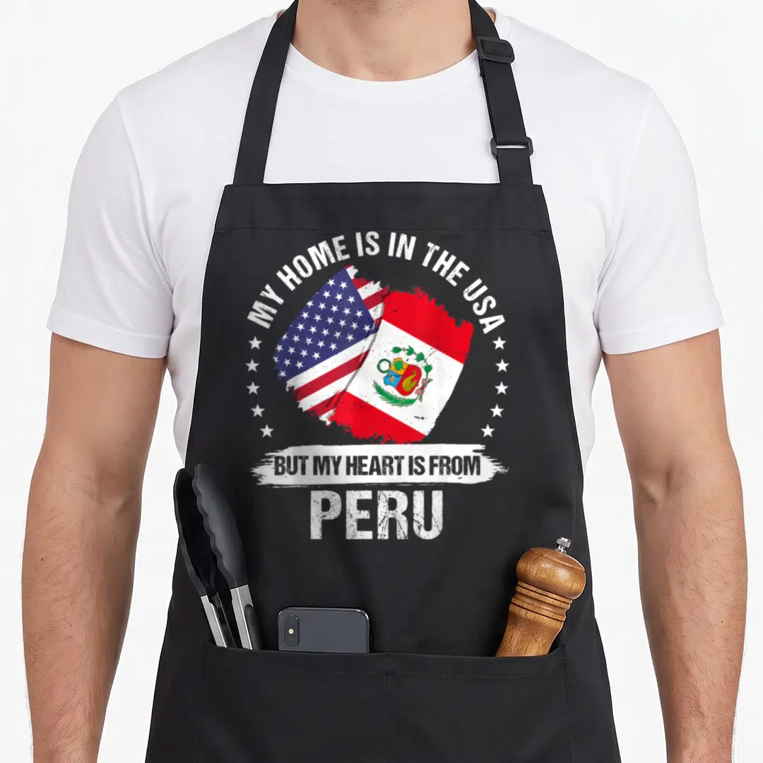Peru patriots apron - My Home Is In The USA But My Heart Is From Peru text with overlapping US and Peru flags — shown on a black cotton canvas apron against a white background