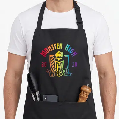Monster pride apron - Rainbow Monster High crest with skull and alumni ribbon text — shown on a black cotton canvas apron against a white background