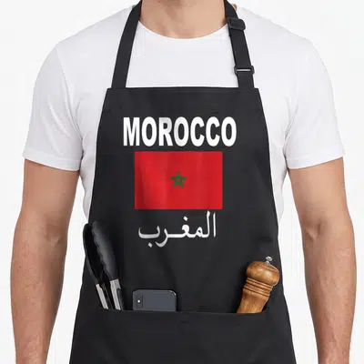Flag moroccan girl apron - Red flag with green star between white MOROCCO text and Arabic script — shown on a black cotton canvas apron against a white background