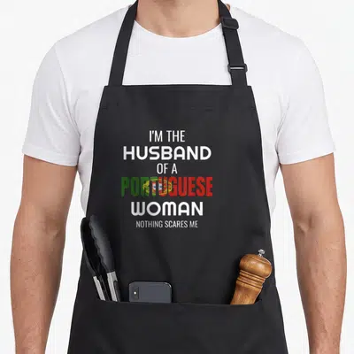 Husband portuguese apron - Stacked text reading I'm the husband of a Portuguese woman nothing scares me with flag colors — shown on a black cotton canvas apron against a white background