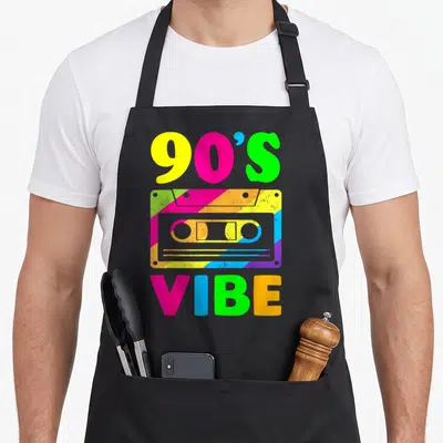 Outfit 90s apron - Neon cassette tape graphic with 90'S VIBE text in yellow pink green blue and purple stripes — shown on a black cotton canvas apron against a white background