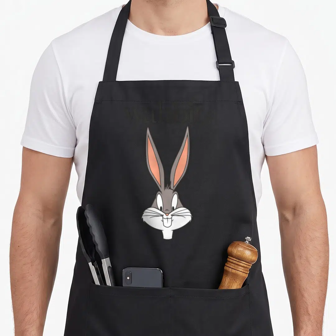 Wabbit bunny apron - Cartoon rabbit head in grey white and pink with wabbit text above — shown on a black cotton canvas apron against a white background