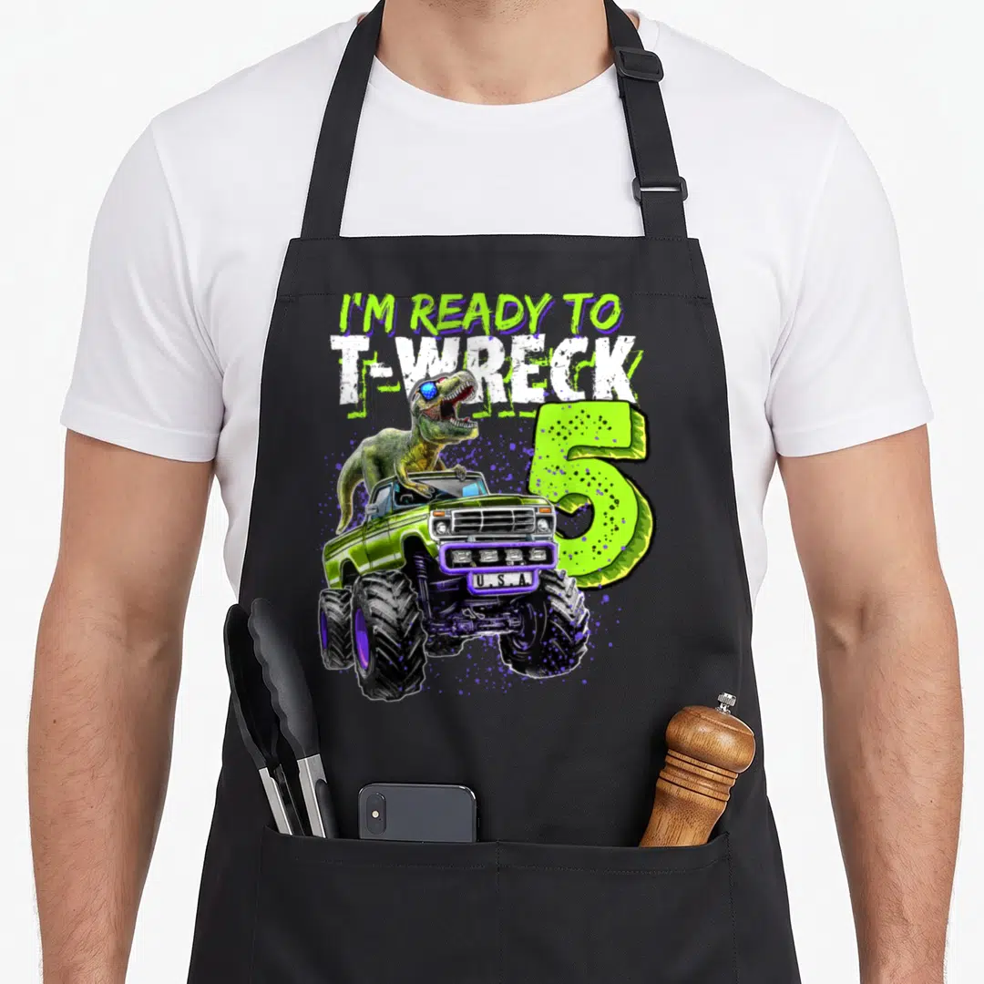 Wreck truck apron - T-Rex in sunglasses driving lime green monster truck next to number 5 and text I'm ready to T-wreck — shown on a black cotton canvas apron against a white background