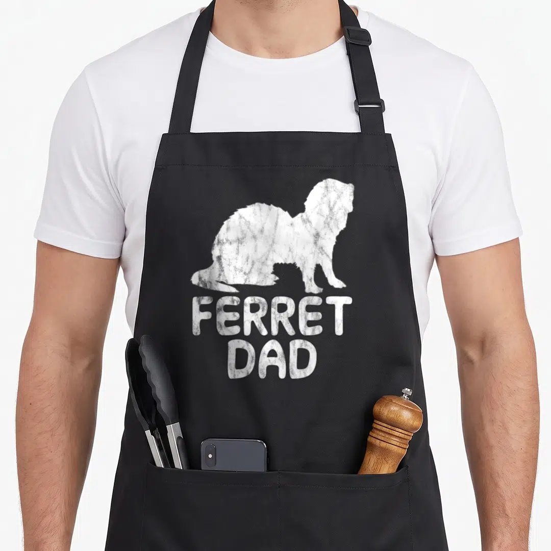 Cute ferret dad apron - White distressed ferret silhouette above stacked FERRET DAD text — shown on a black cotton canvas apron against a white background