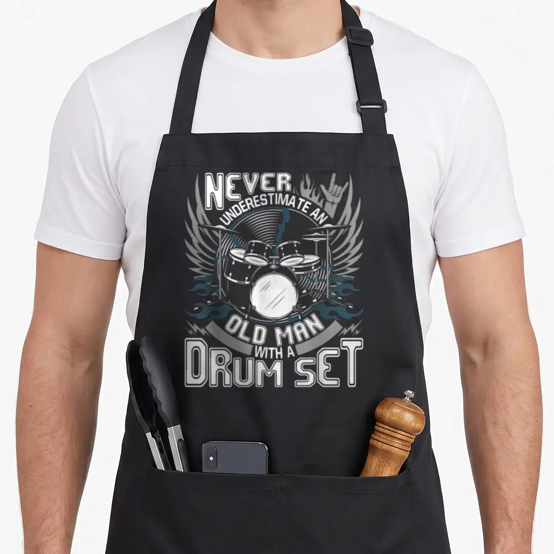 Underestimate black pride apron - Line art of a drum set with wings, flames, and a rock hand symbol surrounded — shown on a black cotton canvas apron against a white background