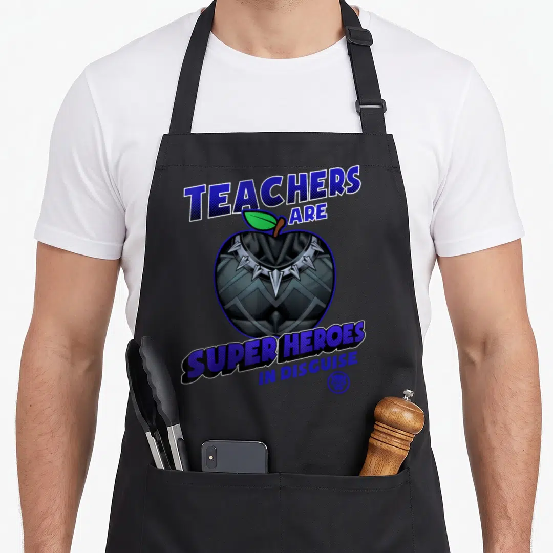 Heroe disguise teacher apron - Text Teachers Are Super Heroes In Disguise around apple with Black Panther mask design — shown on a black cotton canvas apron against a white background