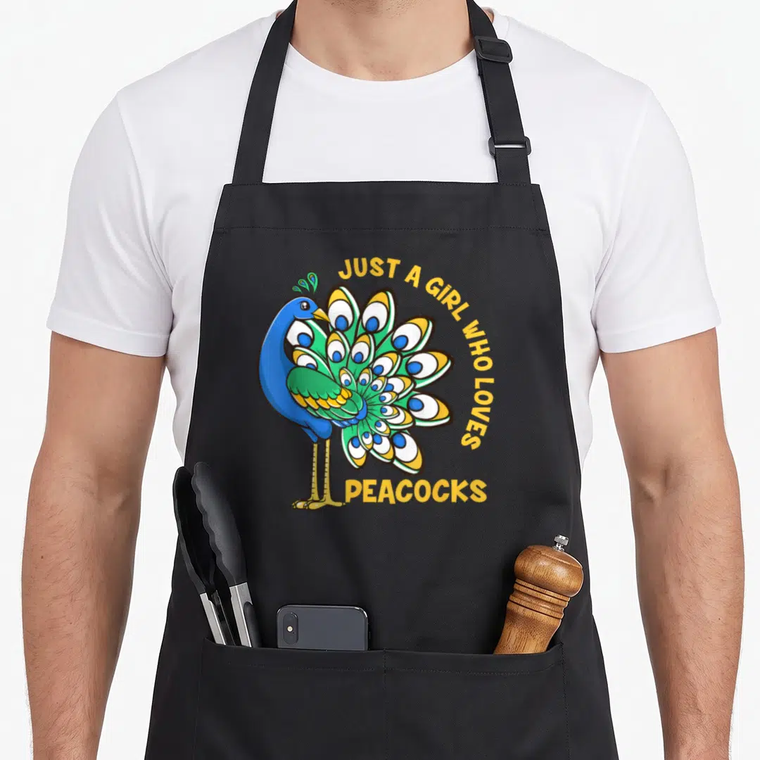 Retro animal apron for grilling - Cartoon peacock in blue and green with yellow text arching over tail feathers — shown on a black cotton canvas apron against a white background
