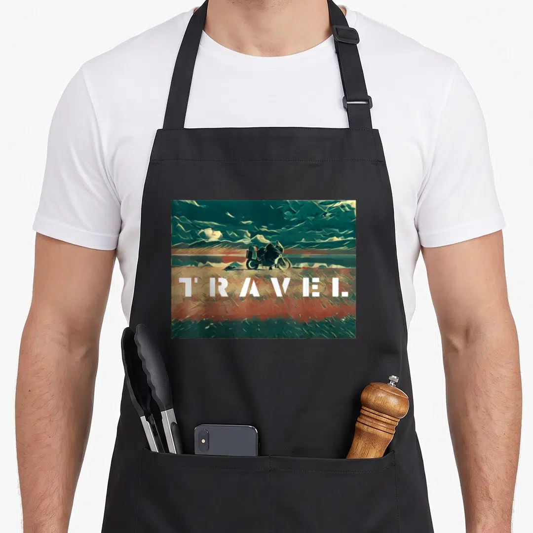 Cute motorcycle bike apron - Realistic motorcycle on teal and brown background with white TRAVEL text across lower — shown on a black cotton canvas apron against a white background