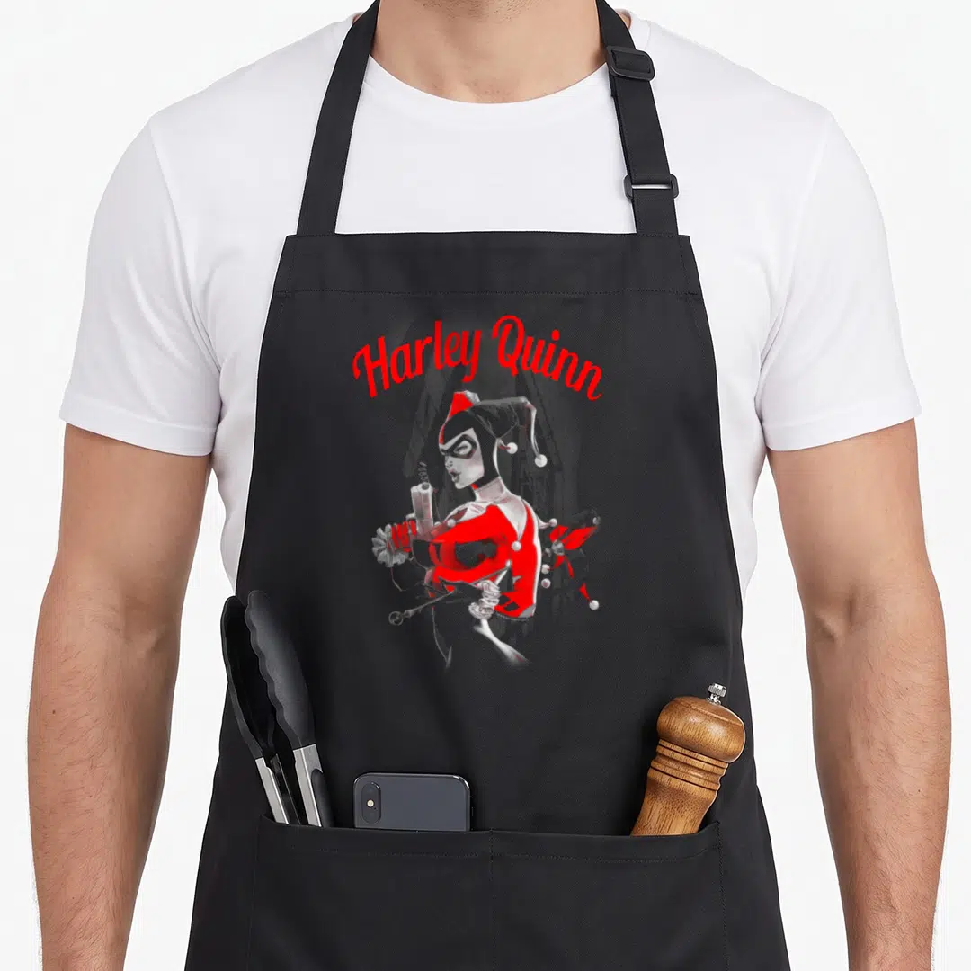 Gun spring apron - Harley Quinn cartoon holding gun and mallet in red and grey with arched text — shown on a black cotton canvas apron against a white background