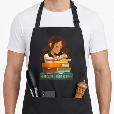 Educated queen apron - Cartoon woman reading behind stacked books with banner text educated latina queen — shown on a black cotton canvas apron against a white background