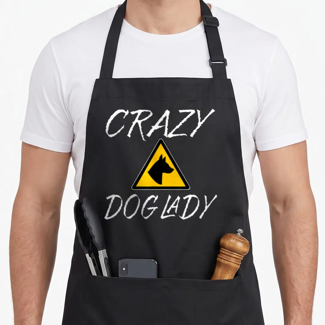 Retro dog cooking apron - Yellow warning sign with black dog silhouette and CRAZY DOG LADY text — shown on a black cotton canvas apron against a white background