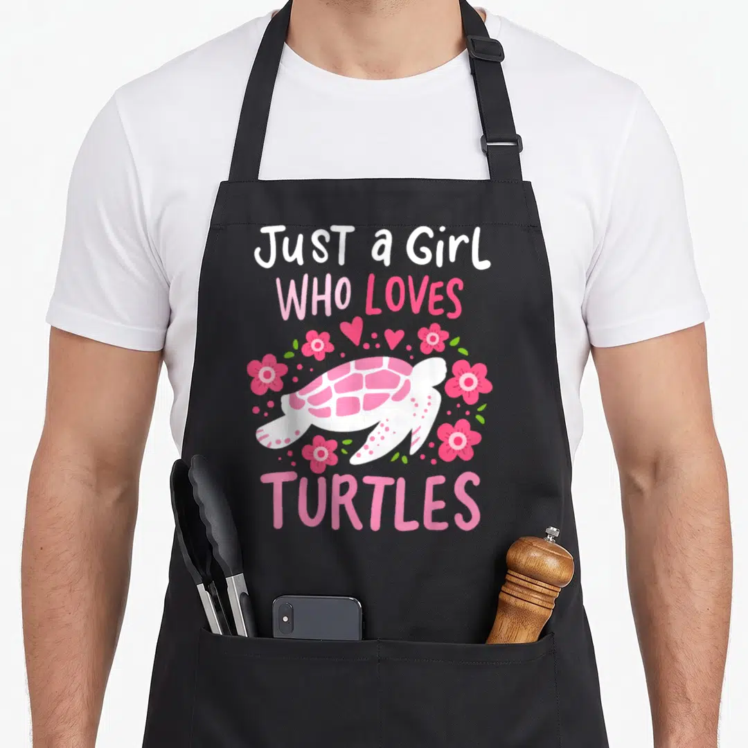 Funny turtle lover apron - Pink and white cartoon turtle surrounded by flowers and hearts with stacked text — shown on a black cotton canvas apron against a white background