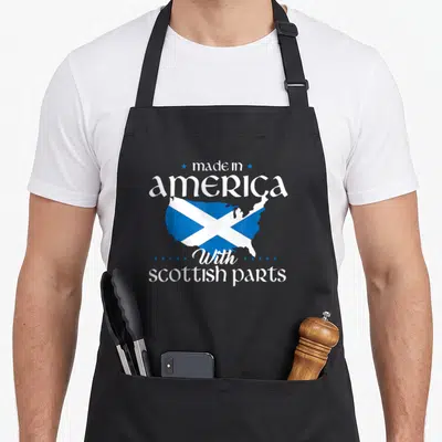 Scottish parts of an apron - USA map filled with blue and white saltire pattern and text made in America with scottish — shown on a black cotton canvas apron against a white background