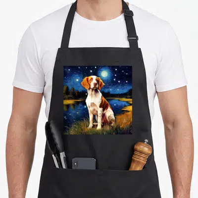 Starry night dog apron - Watercolor Brittany Spaniel dog sitting in grass under swirling blue night sky with yellow — shown on a black cotton canvas apron against a white background